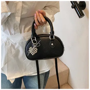 Nahaufnahme der schwarzen Shell-Tasche mit stilvollem, herzförmigem Perlenanhänger.