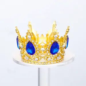 Detalle de una corona real dorada con cristales azules en forma de pera y pedrería