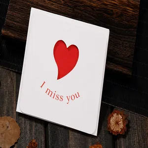 Close-up of minimalist white card featuring a hollow red heart and "I miss you" text.