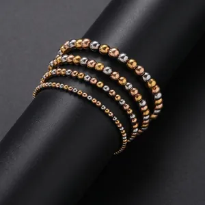 Close-up of stacked gold and silver stainless steel beaded bracelets on a black display stand.