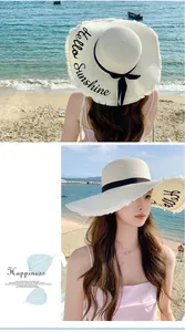 Close-up detail of wide brim straw sun hat with Hello Sunshine script on a sunny beach