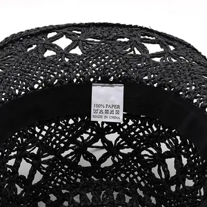 Detail view of the 100% paper material label inside a black hollow woven straw hat.