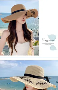 Detail of fashionable straw sun hat with Hello Sun embroidery on wide frayed brim.