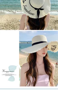 Lifestyle view of women's straw sun hat with fringe brim and black ribbon at the beach