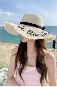 Detail view of women's straw sun hat with 'Hello' embroidery and wide fringe brim