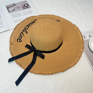 Stylish women's wide-brim straw sun hat with Sunshine embroidery and elegant black bow.