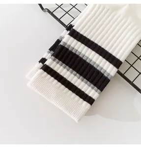 Close-up detail of white ribbed mid-calf socks with black athletic stripes.