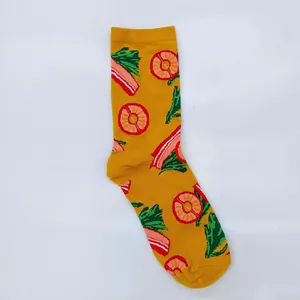 Close-up of yellow cotton crew sock featuring colorful bacon and pineapple patterns