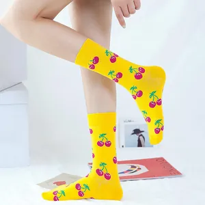 Detail of vibrant yellow socks featuring a red cherry pattern on model legs