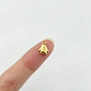 Makroansicht eines kleinen goldenen Pinguin-Anhängers aus Edelstahl auf einer Fingerspitze