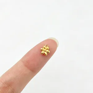 Detaillierte Makroansicht eines kleinen goldenen Blumenanhängers zur Größenreferenz