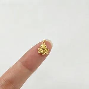 Detailansicht eines kleinen goldenen Oktopus-Anhängers aus Edelstahl auf der Fingerspitze für DIY
