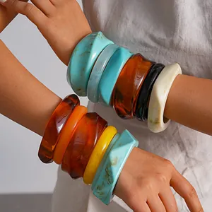 Detail van retro gemarmerde hars geometrische armbanden in levendige kleuren om de pols