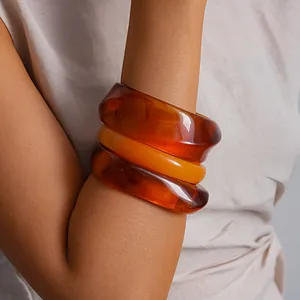 Gedetailleerd overzicht van drie grove vintage amberhars armbanden op de arm van model