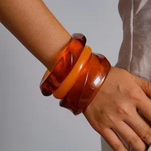 Close-up van retro hars armbanden set met amber marmer en oranje geometrische ontwerpen.