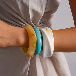 Gedetailleerde close-up van drie gelaagde retro hars gemarmerde armbanden om de pols