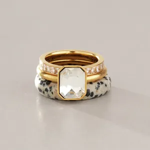 Close-up of stacked stainless steel rings with emerald cut stone and dalmatian stone