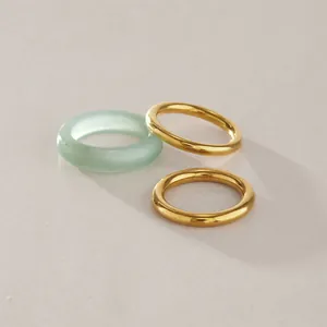 Close-up of minimalist titanium steel gold bands and a light green natural stone ring