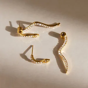Close-up of wavy snake-shaped titanium steel earrings with sparkling white rhinestones.