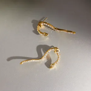 Detail shot of golden snake-shaped stud earrings featuring shimmering inlaid rhinestones