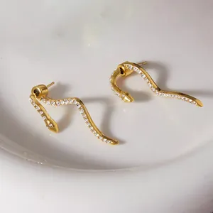 Detailed view of gold snake-shaped earrings with sparkling rhinestones and wavy design