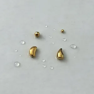 Macro detail of vacuum-plated gold stainless steel spacer beads with water droplets