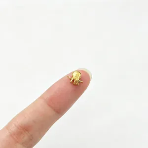 Tiny gold stainless steel octopus bead for DIY jewelry making shown on finger