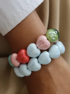 Close-up view of colorful heart-shaped beaded elastic bracelets worn on a woman's wrist