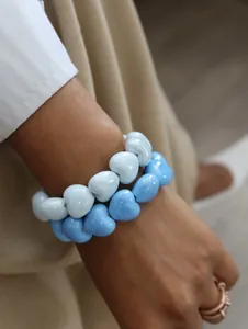Close-up of glossy sky blue and white heart beaded elastic bracelets worn on a wrist