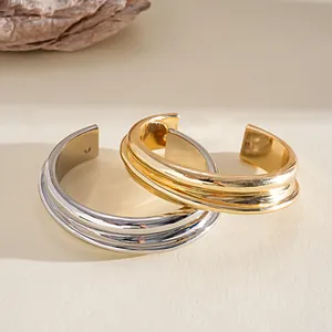 Detailed view of polished gold and silver metallic cuff bracelets with geometric grooves.