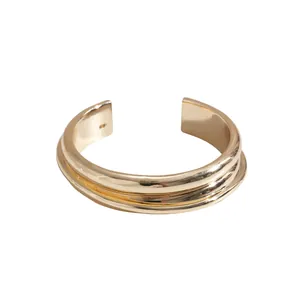 Minimalist gold metallic geometric cuff bracelet with ridged texture and glossy finish