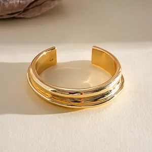 Detailed macro view of wide gold metallic open cuff bracelet with tiered texture