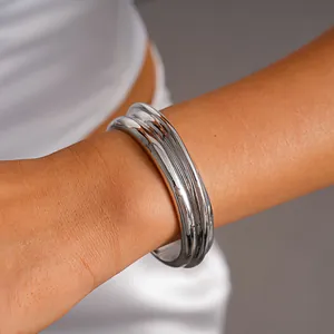 Close-up view of a minimalist silver-toned textured metal open cuff bangle on a wrist