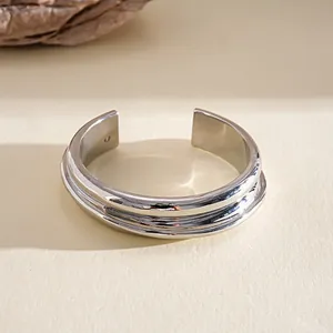 Detail view of a silver minimalist metal cuff bracelet with ribbed geometric texture