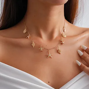 Primo piano dettagliato di una collana dorata con ciondoli a stella marina e tartaruga indossata.