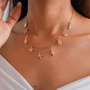 Dettaglio di una collana dorata con ciondoli a forma di stella marina, conchiglia e tartaruga.