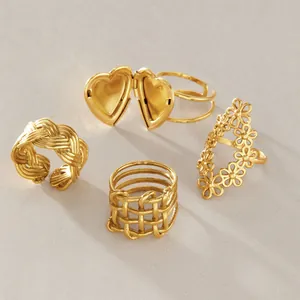 Detailed view of four unique gold-plated stainless steel rings with floral and heart designs