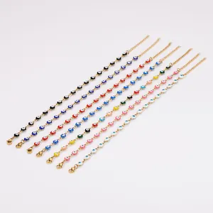 Gros plan de bracelets de cheville œil bleu colorés en émail sur des chaînes dorées.