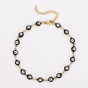 Détail d'une chevillère en acier doré avec des perles noires œil porte-bonheur