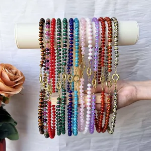Detailed macro view of vibrant colorful natural stone beaded necklaces on a white display stand