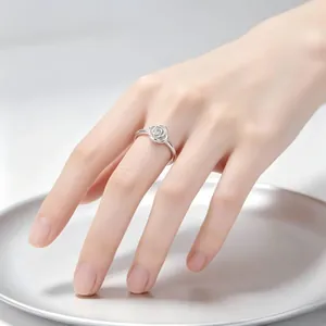 Detailansicht eines eleganten silbernen Rosenrings an einer Hand über einer Metallplatte.