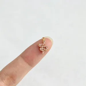 Vergoldeter Edelstahlanhänger in Schlangenform mit rosa Steinen auf dem Finger