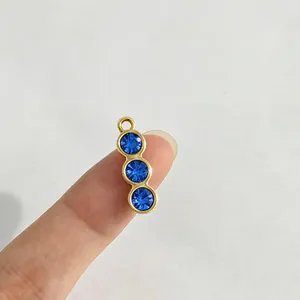 Detailansicht eines goldenen Edelstahl-Anhängers mit drei funkelnden blauen Straßsteinen