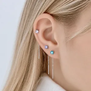 Eleganti orecchini a catena in titanio con borchie di zircone da 4 mm sull'orecchio di una modella
