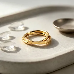 Close-up detail of interlocking double gold stainless steel bands on a textured tray surface