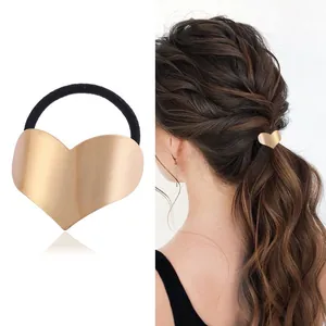 Rear view detail of a model wearing a matte gold heart-shaped hair tie in a ponytail