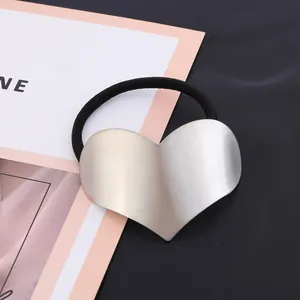 Close-up detail of a minimalist heart-shaped brushed alloy metal hair rope tie
