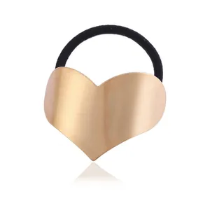 Close-up detail of a brushed gold heart-shaped metal hair tie with a black elastic band.