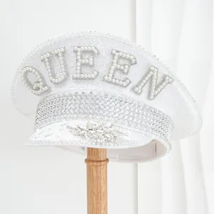 Detailed view of a white sparkly captain hat with QUEEN pearl letters and rhinestones