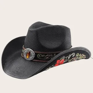 Detalle de sombrero de vaquero de paja negra con bordado rojo y banda decorativa de ámbar.
